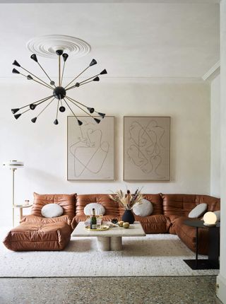 A tall room with a statement pendant light and sectional leather sofa