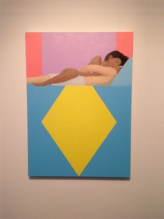 A painting with a white male and brown female kissing each other lying down. The colour blocks include a blue lower third covered with a yellow diamond. An orange and pink top third.