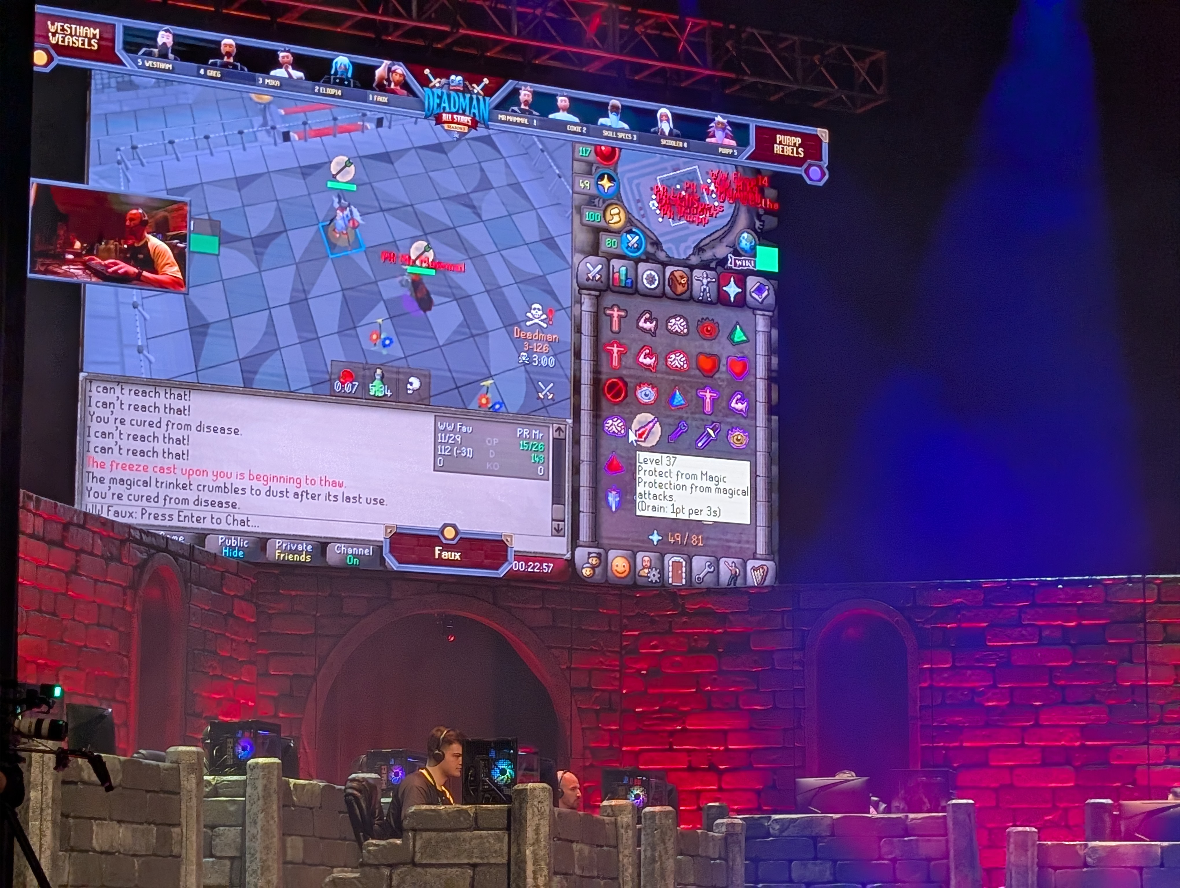 Shot of Old School RuneScape Deadman All Stars Tournament stage, with crenelated walls, players at PC, and RuneScape PvP projected behind.
