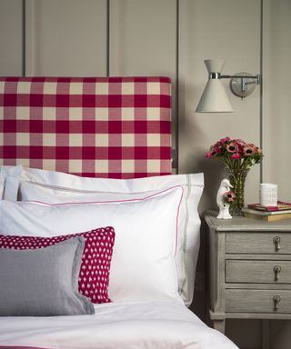 Country-style girls' bedroom ideas example, with panelled taupe walls and red gingham headboard above white bed linen.