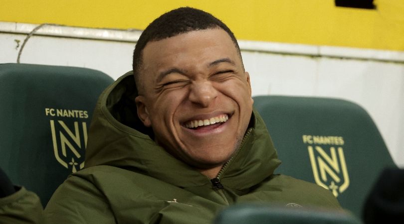 Kylian Mbappe smiles as he sits on the bench during Paris Saint-Germain&#039;s match against Nantes in February 2024.