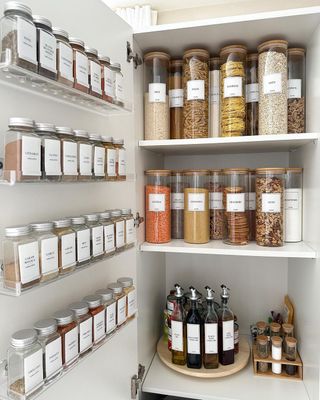 A kitchen cupboard with multiple jars on the door and inside it