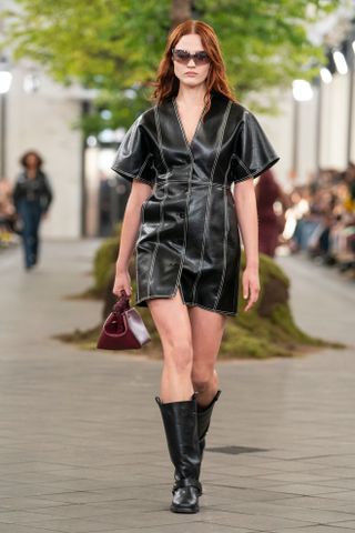 a Ganni model walks the spring/summer 2024 runway wearing a leather mini dress and Mid Shaft Biker Boots