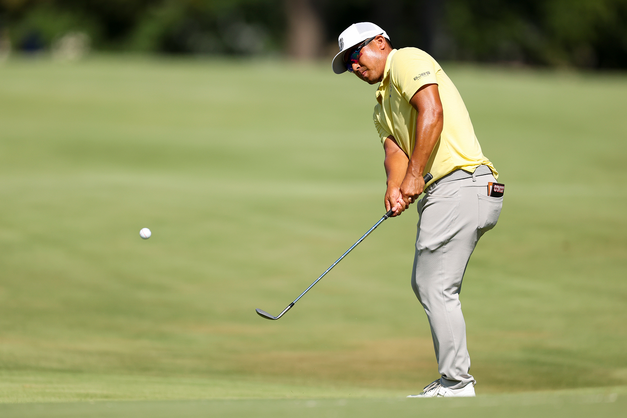 Kurt Kitayama just past impact with a wedge after playing a chip shot