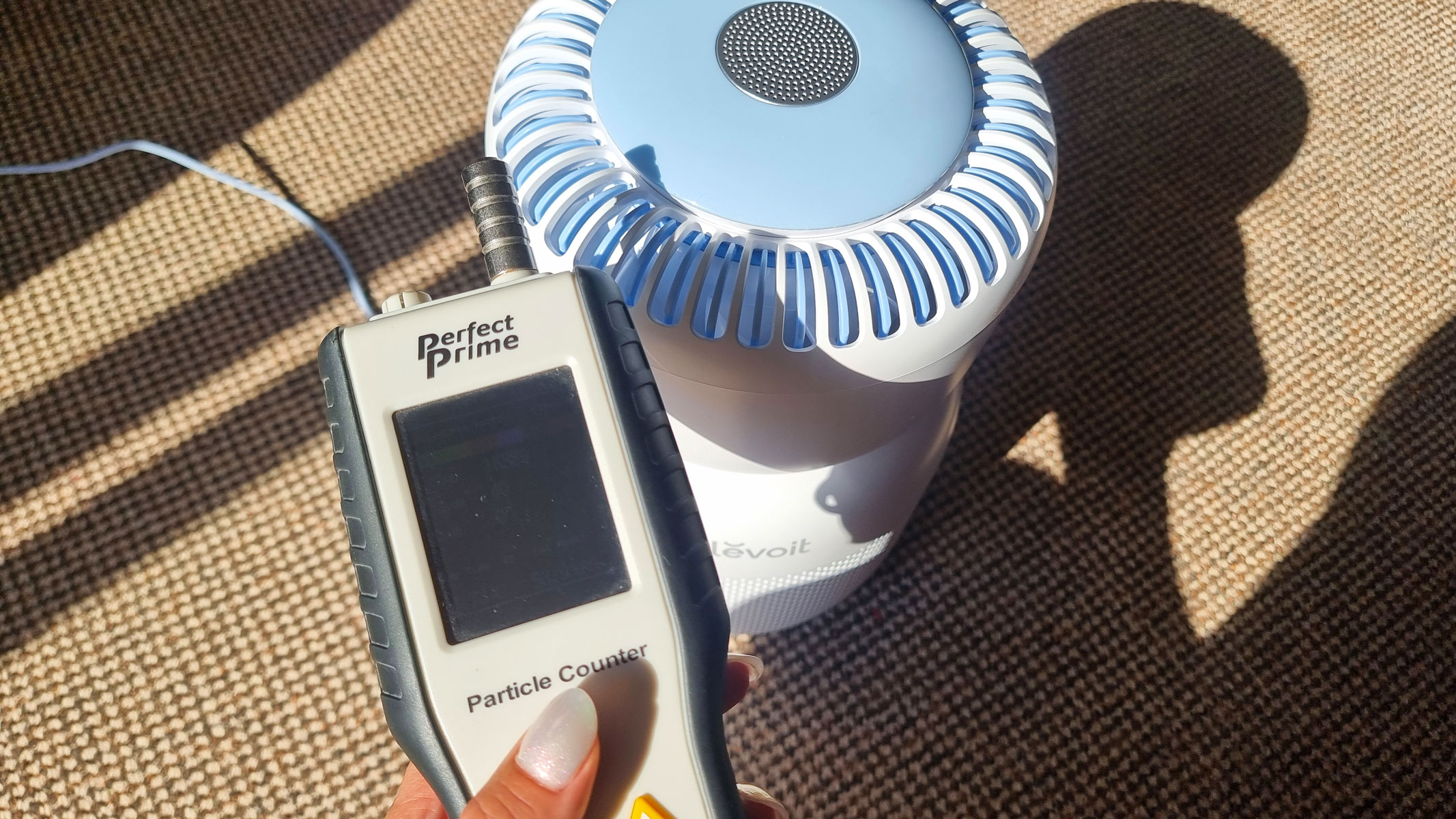 A close-up picture of our reviewer testing the Levoit Sprout air purifier with an air particle monitor
