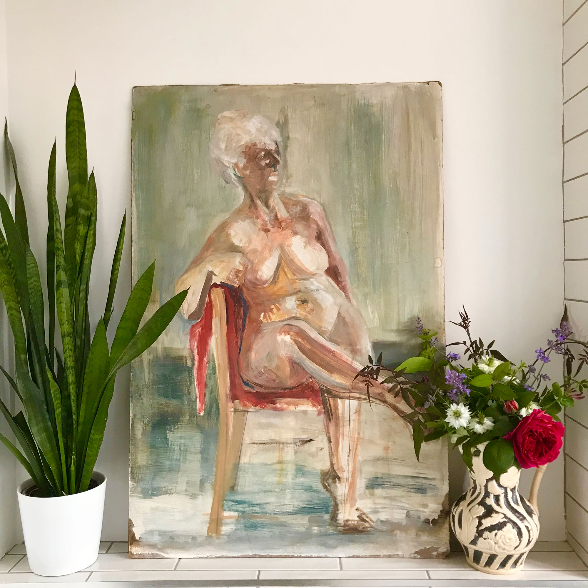 Painting of a nude woman on a chair resting against wall beside snake plant and jug of flowers