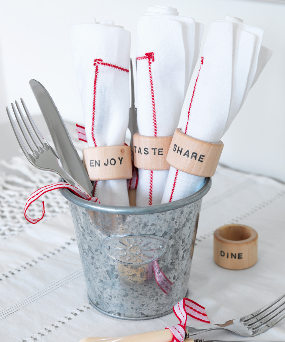 rolled red and white Christmas napkins held by wooden holders in silver bucket