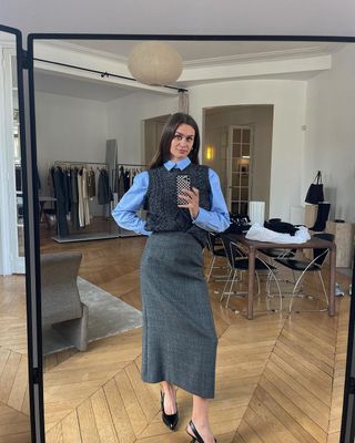 @annelauremais in blue button down, sweater vest, and grey skirt