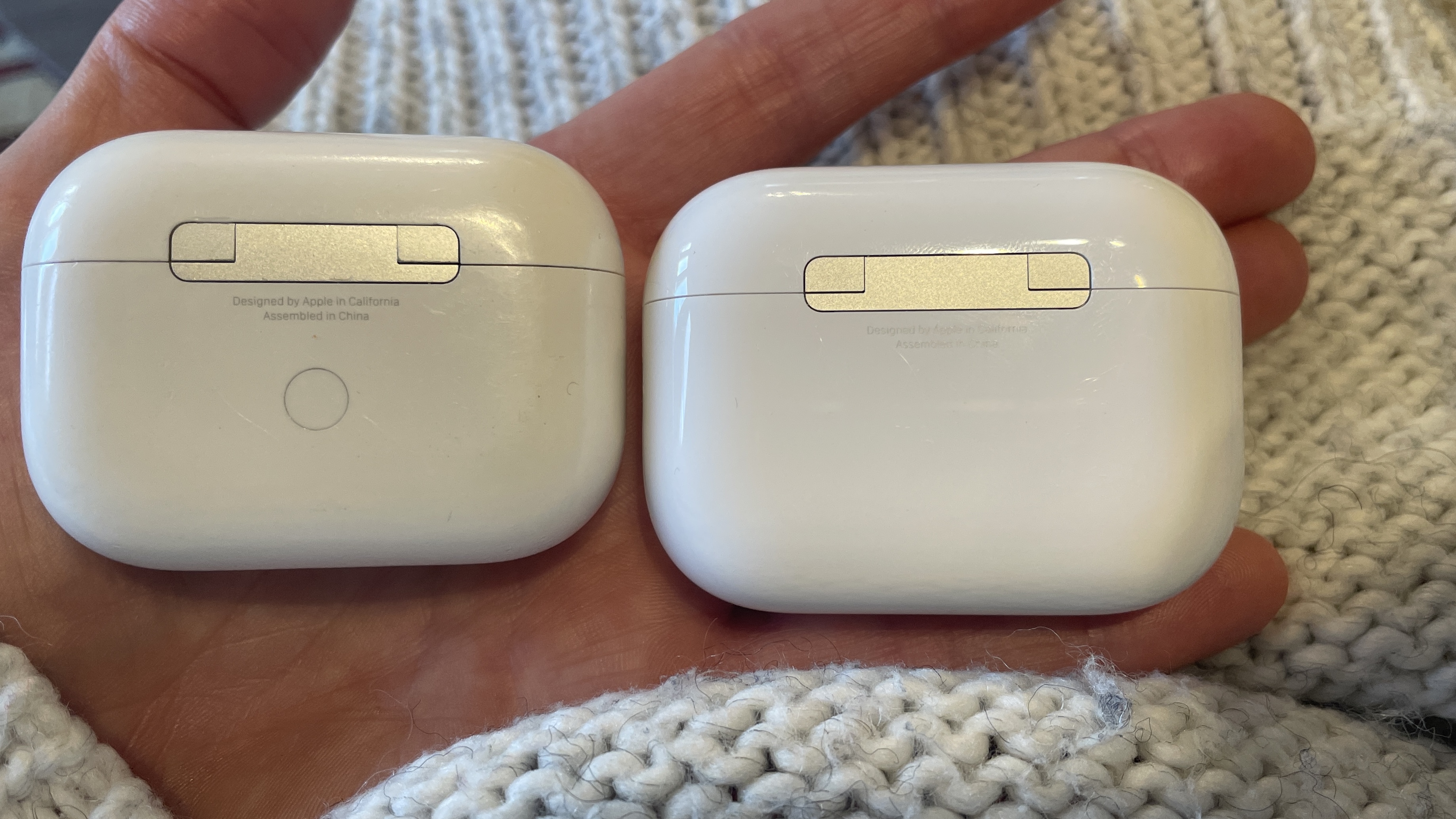 Apple AirPods Pro 3 held in a hand, with beige woollen background