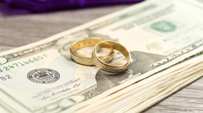 Wedding rings sit atop a stack of cash.