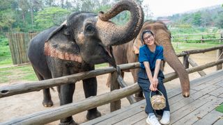 Woman smiling next to elephants