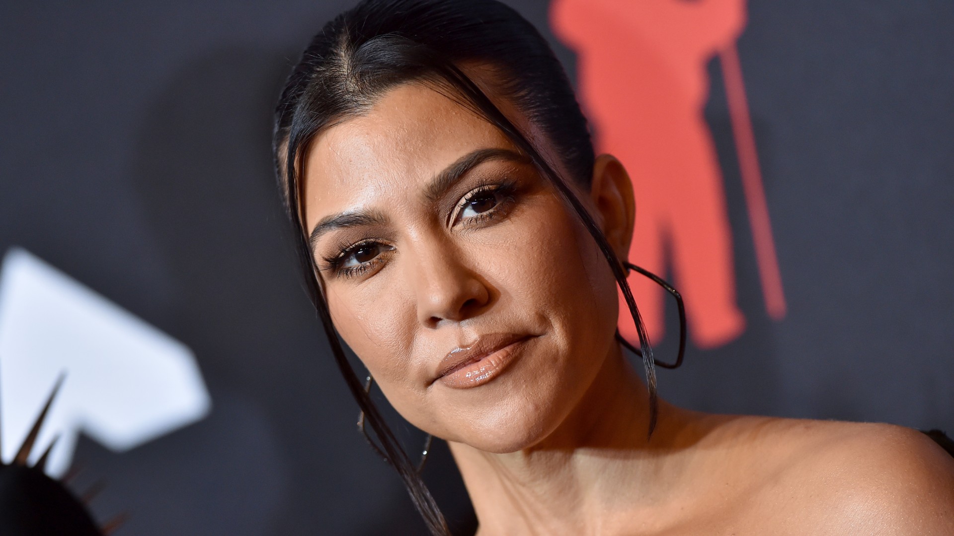 a close up photo of a woman with dark hair posing in front of a dark background on a red carpet