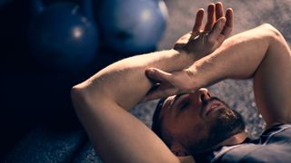 A man lying on the gym floor exhausted