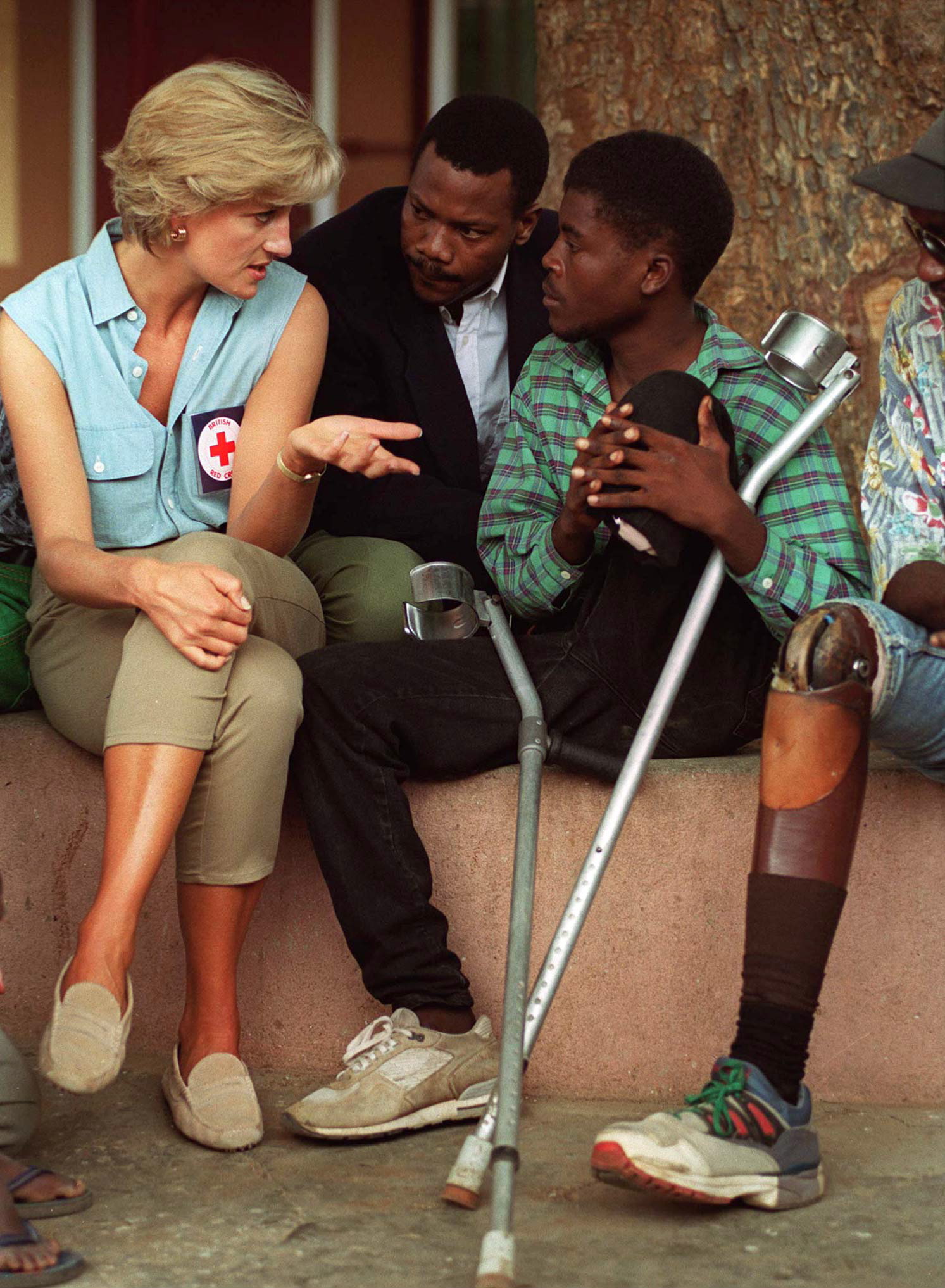 Princess Diana sitting down talking with landmine survivors in Angola