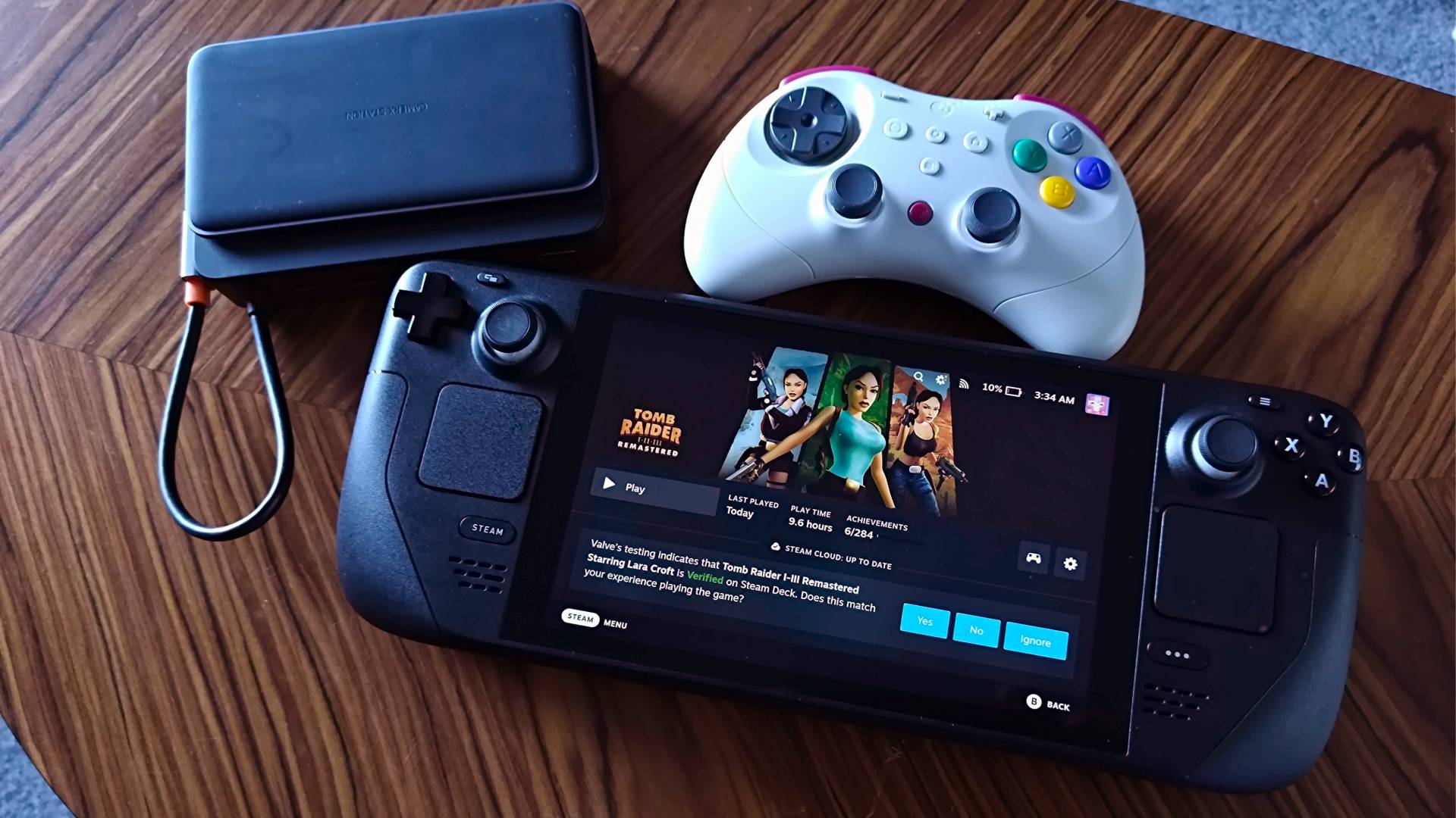 Steam Deck LCD next to Baseus docking station and Gulikit Elves 2 Pro controller on woodgrain table.