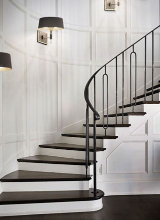 curved period staircase with wall panelling and wall lights