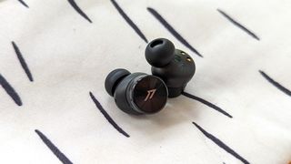 The 1More PistonBuds Pro wireless earbuds resting on a pillow