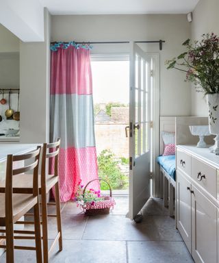 what color drapes/curtains are best for summer, kitchen with pink and blue striped door curtain, stone kitchen with stone cabinets, flagstone floor, flowers, basket of flowers
