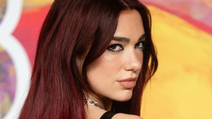 Dua Lipa with red hair in front of a backdrop