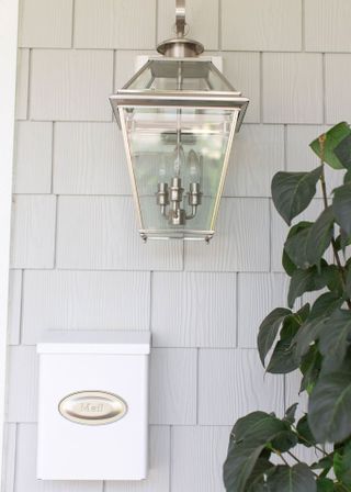 White cladded wall with a white mailbox under a wall lamp.
