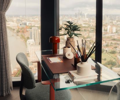 A candle burning on a glass desk in an apartment with large windows