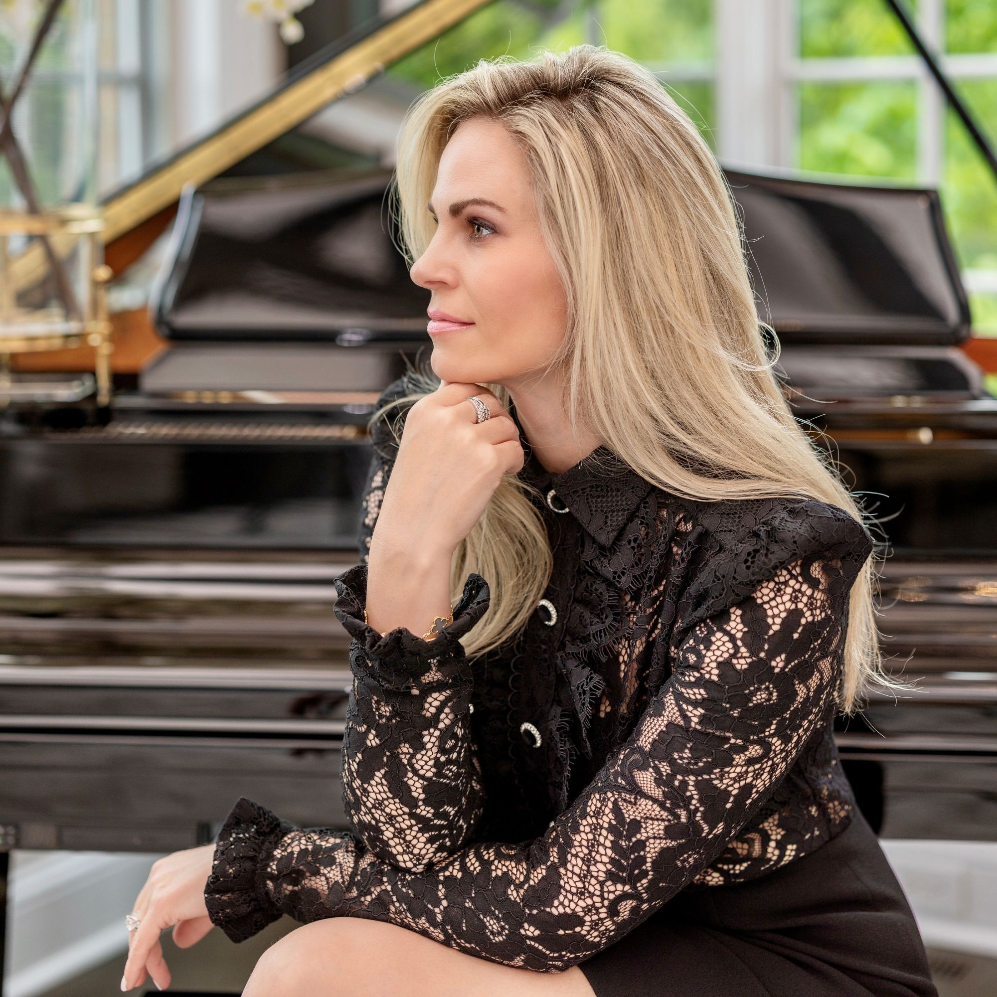 A picture of Janet Linley in a black dress next to a piano