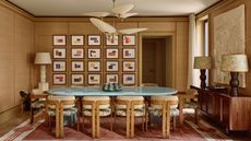 mid-century modern dining room with statement pendant light, console table with two table lamps, and a lamp in the corner of the room, with light blue table and timber chairs, and a gallery wall of art