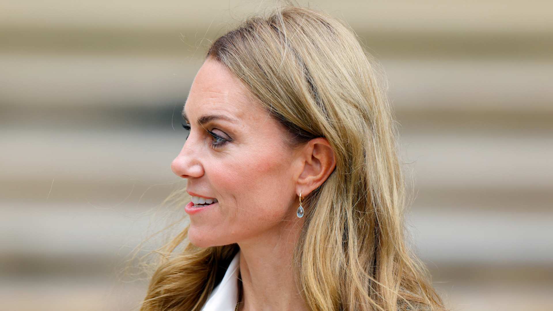 Kate Middleto smiling and turning her head to the side in front of a staircase