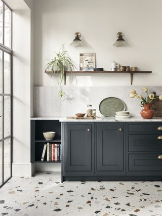 A kitchen with blue cabinetry and terrazzo style floor tiles