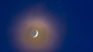 The conjunction of the waxing 4-day-old crescent Moon below the Pleiades, and set in a slightly hazy sky. The haze adds the colourful lunar corona halo around the bright crescent of the Moon from diffraction effects in the high icy clouds. Earthshine is visible on the dark side of the Moon