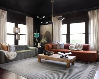 Black living room with orange sofa and wood coffee table