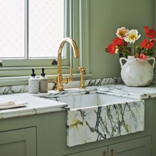 sage green cabinets and walls with marble effect sink and gold mixer tap