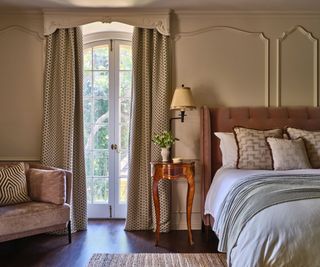 bedroom with taupe paneled walls and patterned cushions