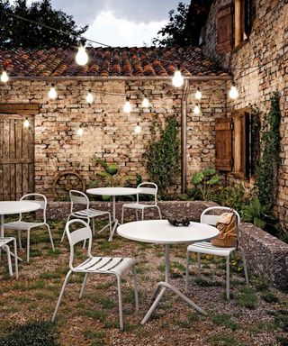 outdoor space with bistro tables and chairs, brick walls and festoon lights