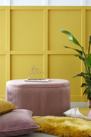 A pink fluted ottoman sits in front of a yellow background reeded trend