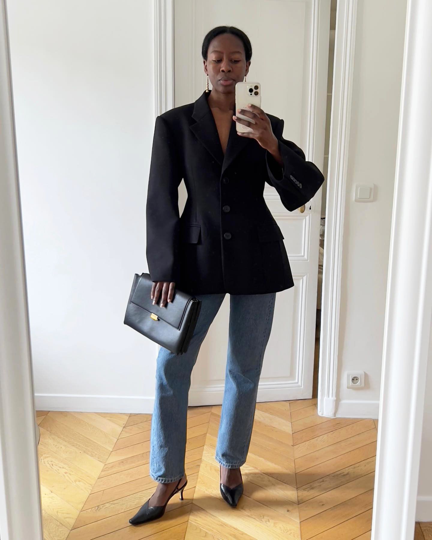 Sylvie Mus wearing a cinch-waist blazer, blue jeans, and pointed-toe slingbacks.