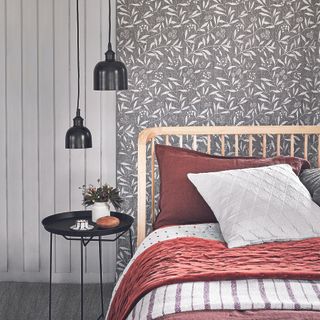 Bedroom with patterned wallpaper, white bed and bedside table.