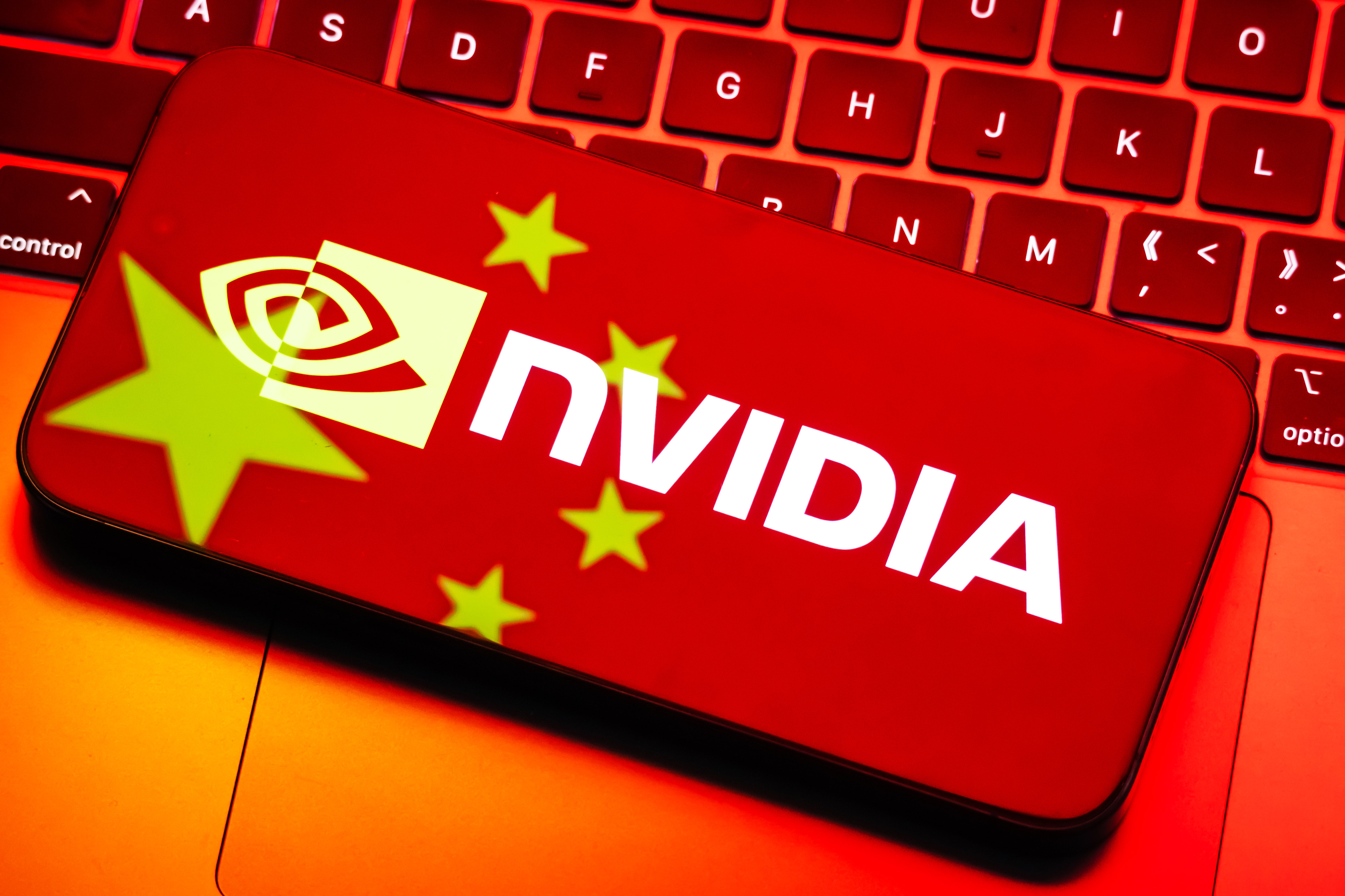 CHONGQING, CHINA - JULY 17: In this photo illustration, the logo of Nvidia Corporation (NASDAQ: NVDA) is displayed on a smartphone screen, with the reflection of the Chinese national flag from a computer screen visible on the device, placed on a red-lit keyboard, on July 17, 2025 in Chongqing, China. (Photo illustration by Cheng Xin/Getty Images)