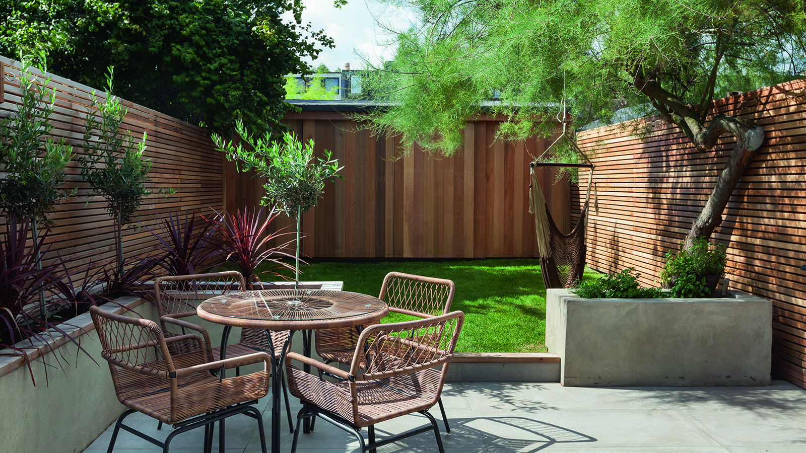 A small garden with round table and lawn with wooden fence panel boundary