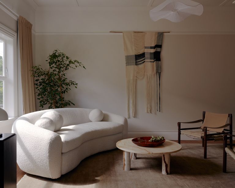 A living room with a white curving sofa and an organic chair