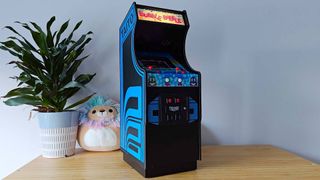 Quartercade Taito Bubble Bobble arcade machine with marquee illuminated sitting on woodgrain surface 