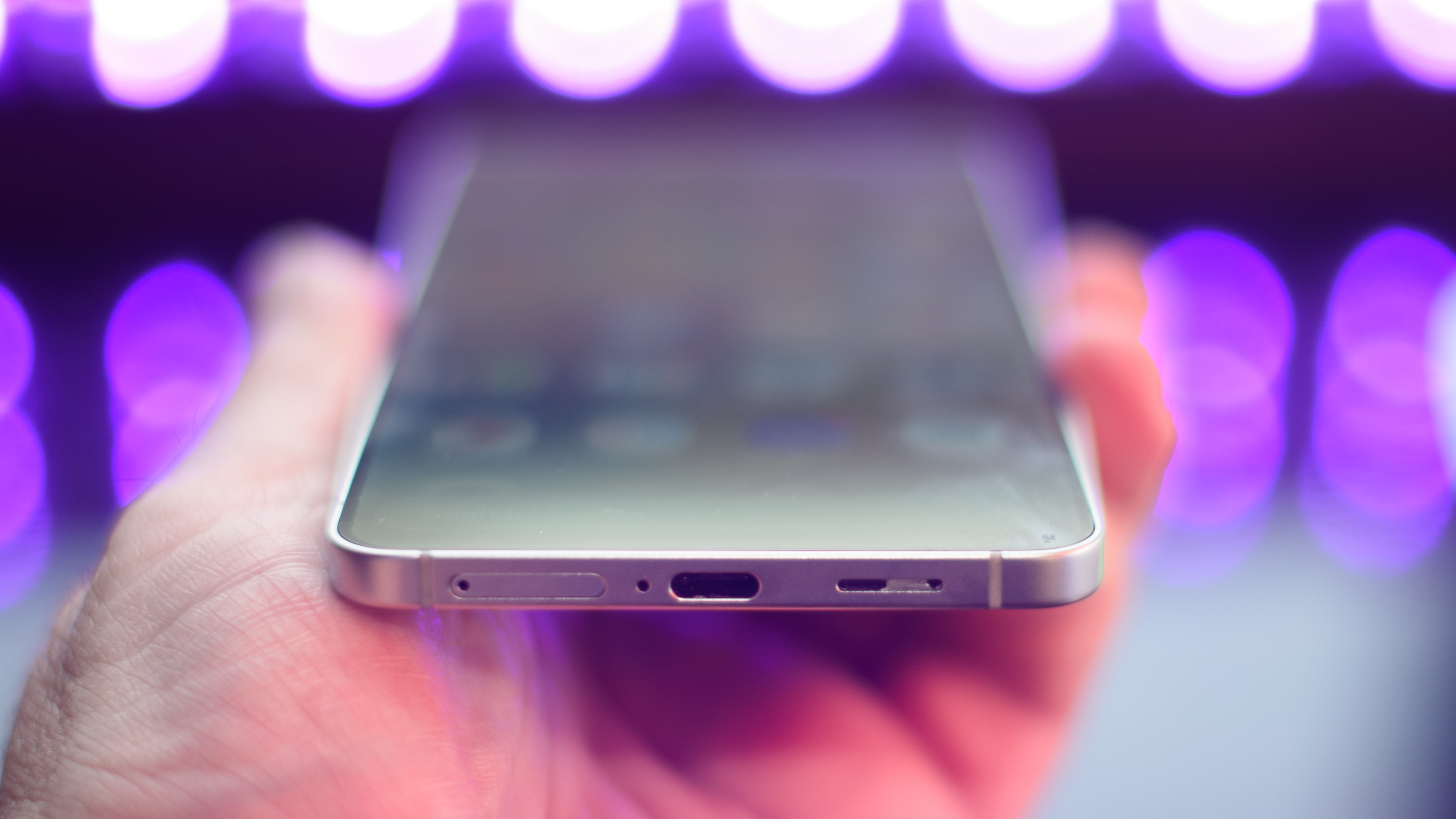 Samsung Galaxy S25 Edge from the bottom with black lights blurred in the background