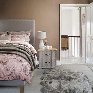 Neutral bedroom with grey bed, wooden bedside table and faux fur rug