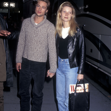 Gwyneth Paltrow wears a 90s autumn jeans outfit. On set of The Devil's Own in New York, 1996 she wears a blue denim jean, black v neck jumper, white t-shirt. She finishes the look with chuck taylors and a black bag with a issue of W hanging out. This image was recently taken from Getty. 