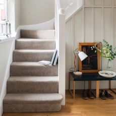 Hallway with wooden floor and carpeted staircase decorated in neutral colours