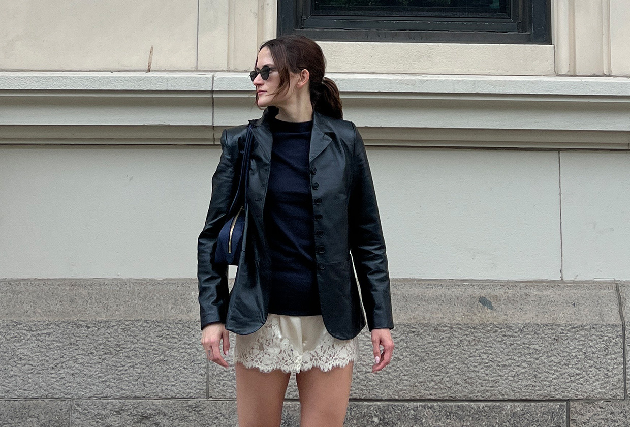 Eliza Huber wearing a leather blazer, navy sweater, ivory lace shorts, and black flats.