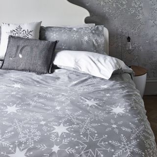snow flake pattern printed bedsheet with grey pillow covers in grey walled room