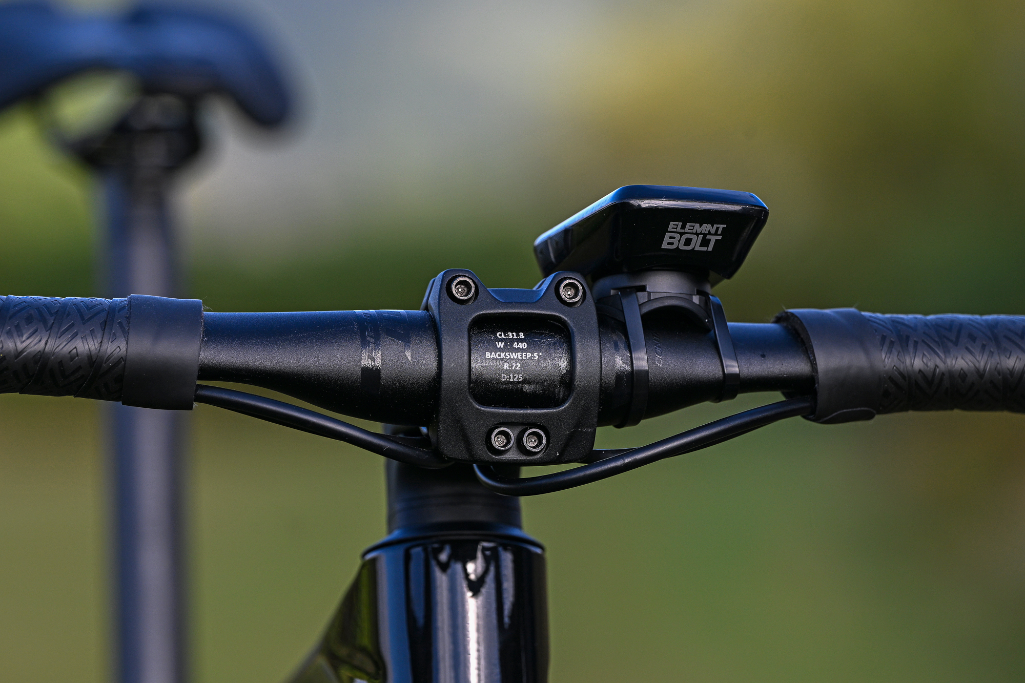 close up of the front of the stem and handlebar on a black bike with a computer on the handlebar