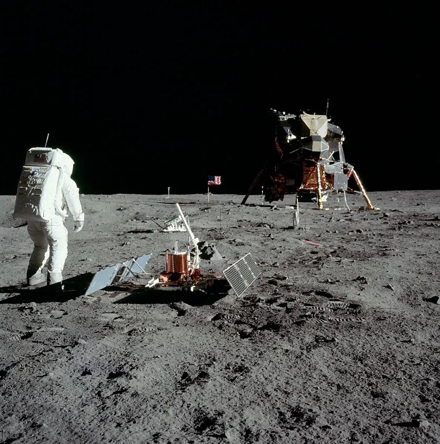 NASA Space Technology astronauts in bulky spacesuits walk on the grey dusty surface of the moon