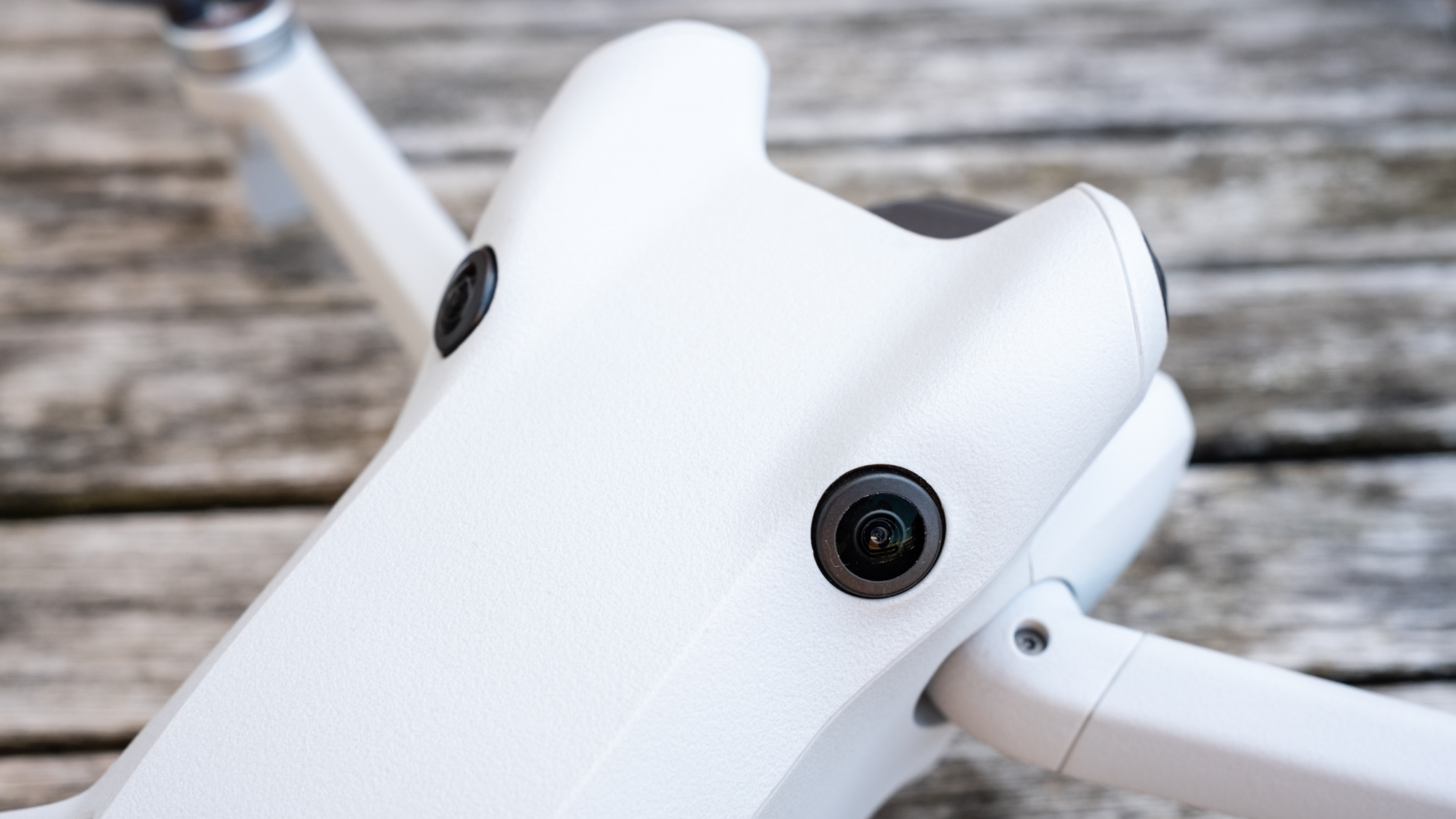 Close-up view of two camera lenses on the body of a white DJI Mini 4 Pro drone.